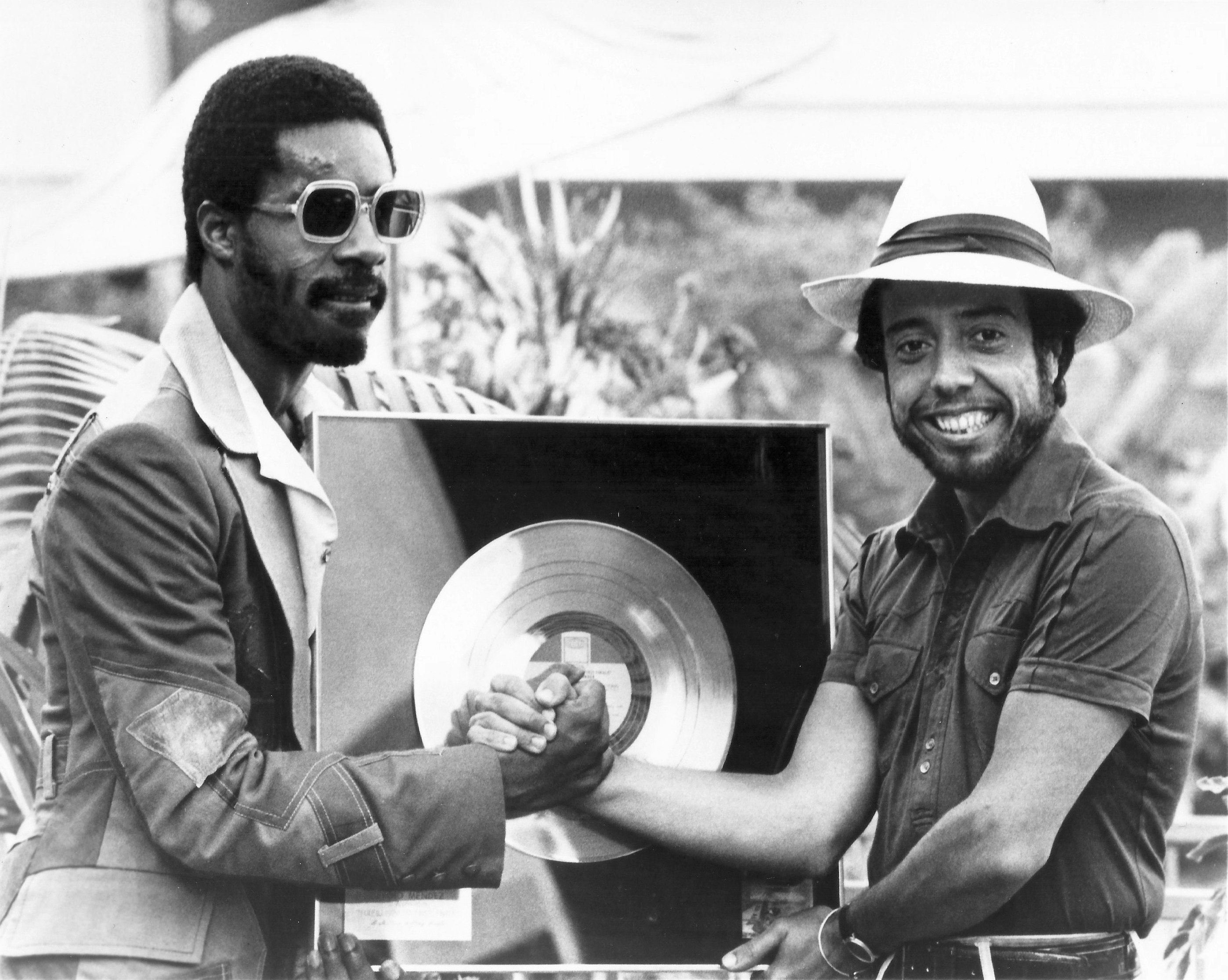 Stevie Wonder and Sergio Mendes with a gold record.